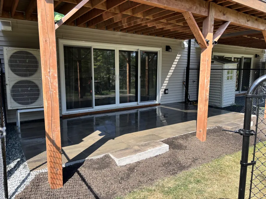 Stone patio being laid beneath a covered deck with large sliding glass doors — hardscaping project in Halifax, Nova Scotia