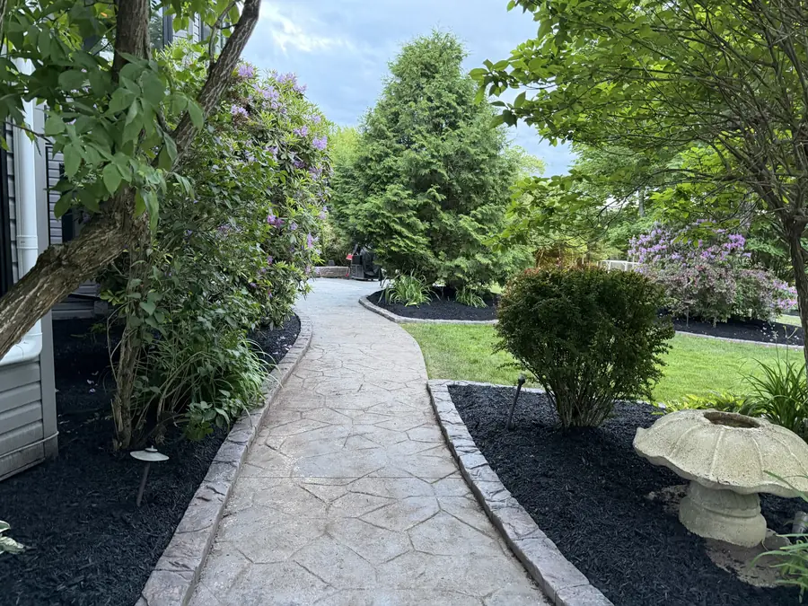Winding stamped stone garden path lined with shrubs, rhododendrons and mulch beds — landscaping project in Halifax, Nova Scotia