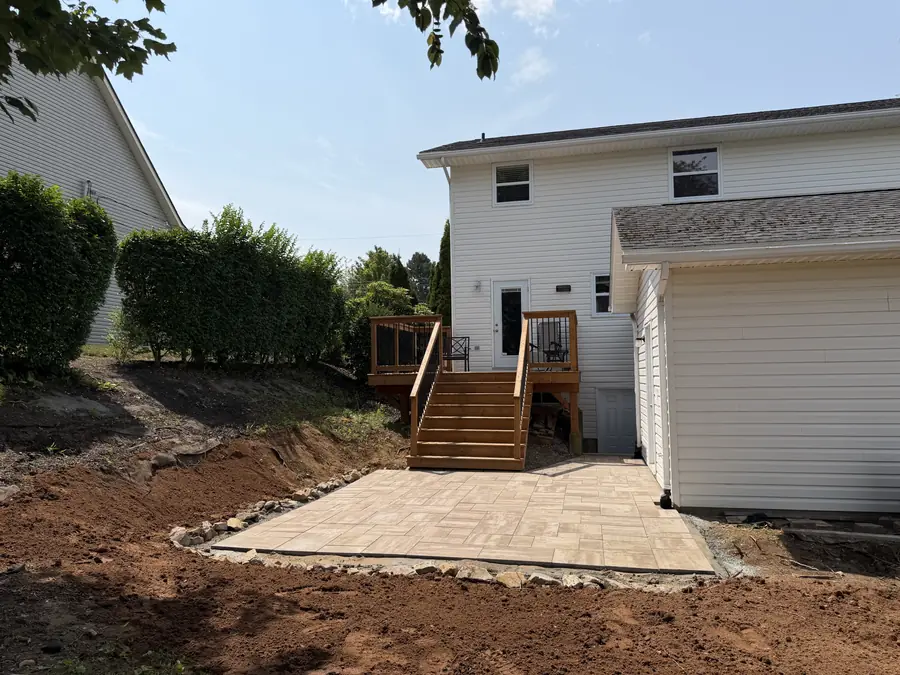 Paver patio laid at the base of back deck steps on a freshly graded yard — hardscaping project in Halifax, Nova Scotia