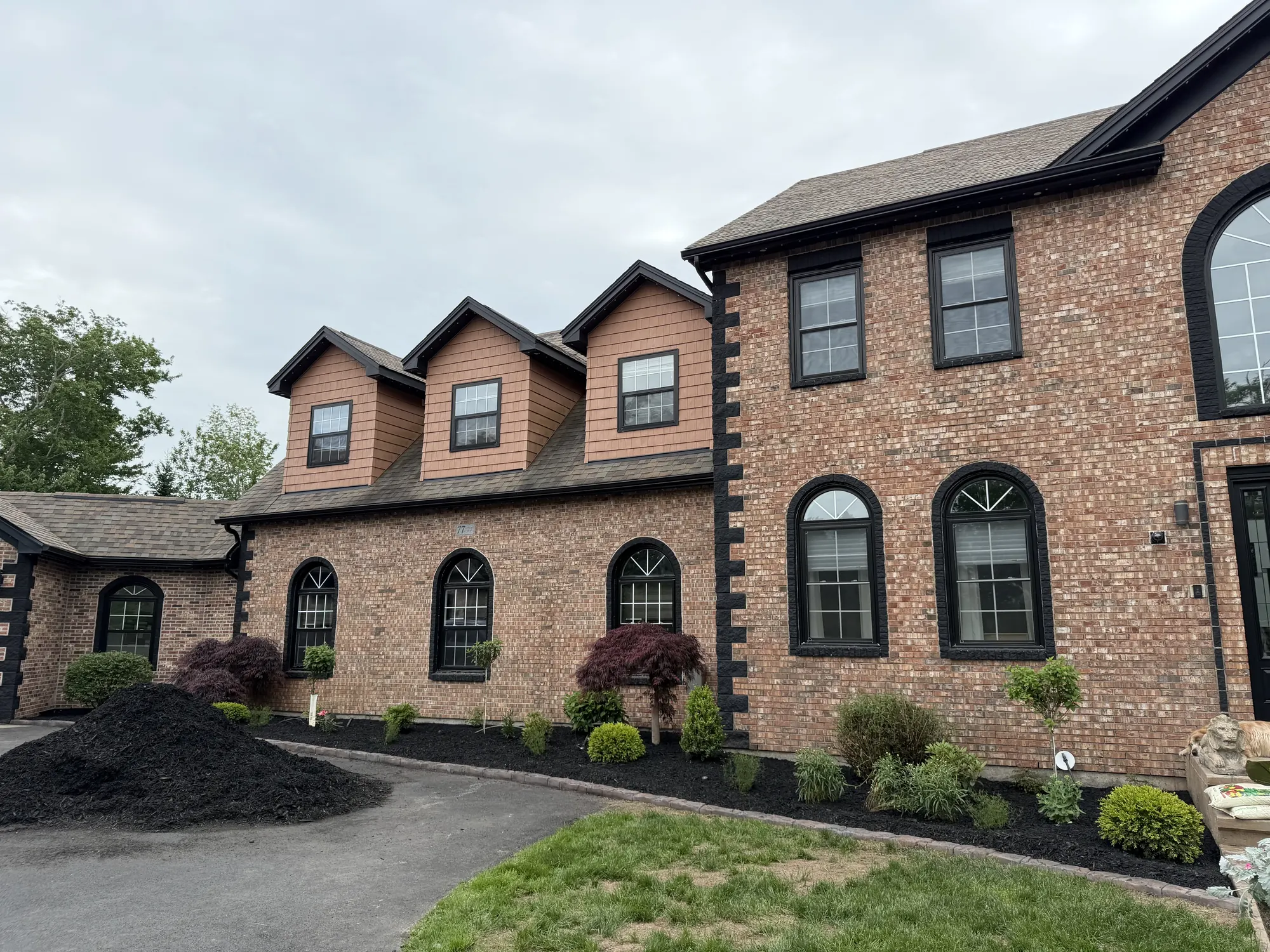 Brick home with freshly mulched garden beds, shrubs and a Japanese maple along the front