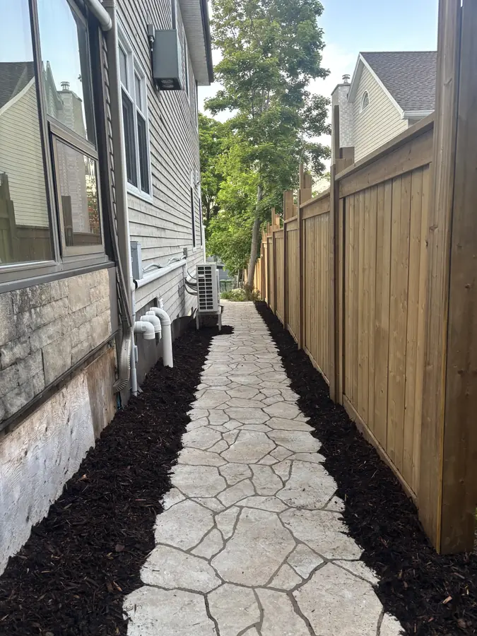Stamped stone side walkway with black mulch beds and a cedar privacy fence, a landscaping project in Halifax, Nova Scotia